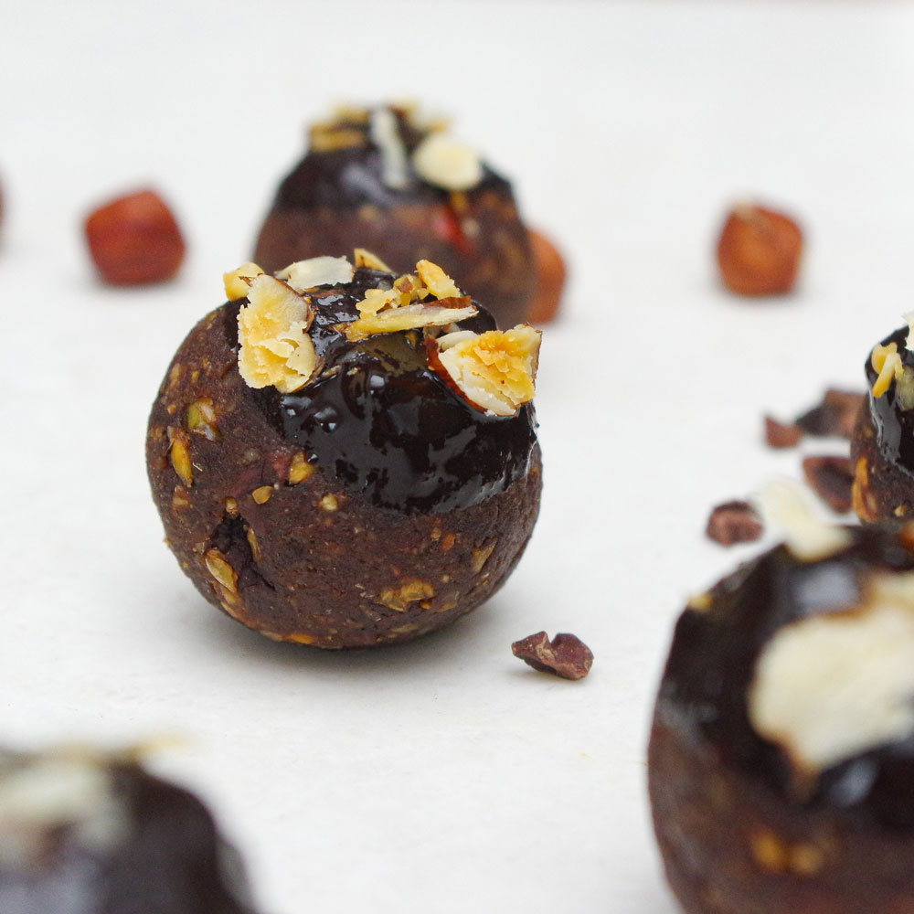 Nahaufnahme von proteinreichen Energiebällchen mit Haselnüssen und Kakaonibs.